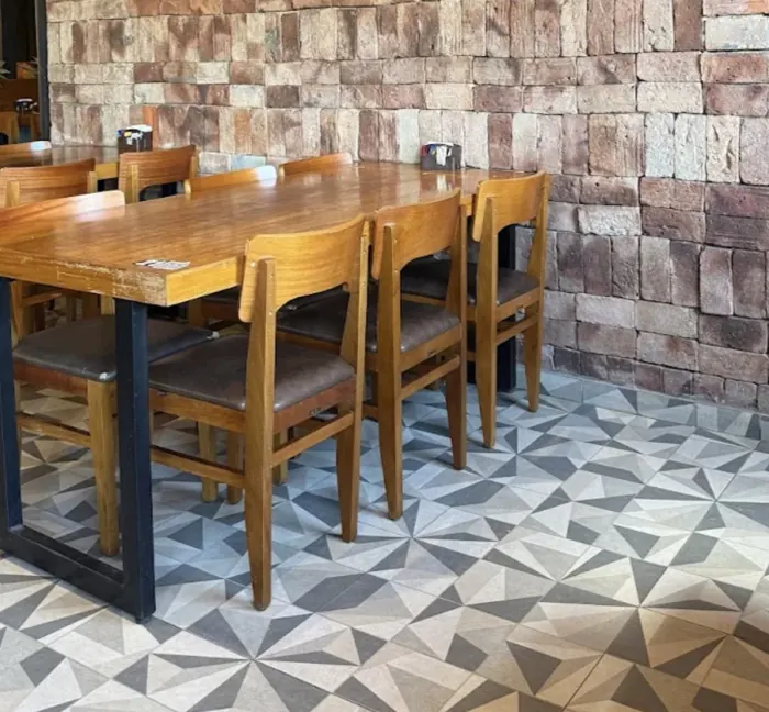 Mesa de madeira com parede de pedra e piso de ladrilho