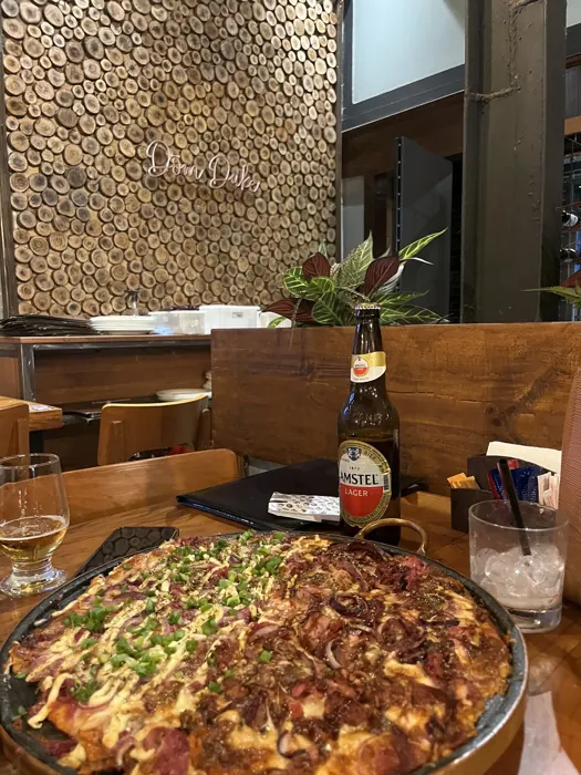 Pizza artesanal com o letreiro neon Dom Duke ao fundo